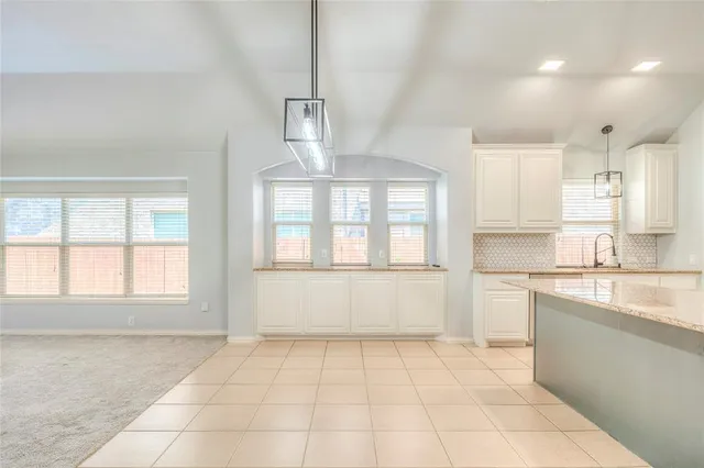 a large white kitchen with cabinets a sink a window and stainless steel appliances