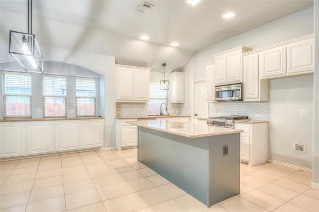 a large kitchen with stainless steel appliances granite countertop a stove a sink dishwasher and a refrigerator