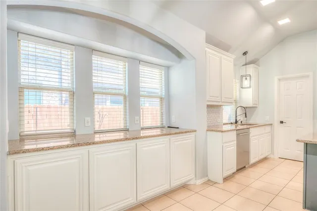 a kitchen with white cabinets and a window