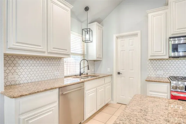 a kitchen with granite countertop a sink stainless steel appliances and cabinets