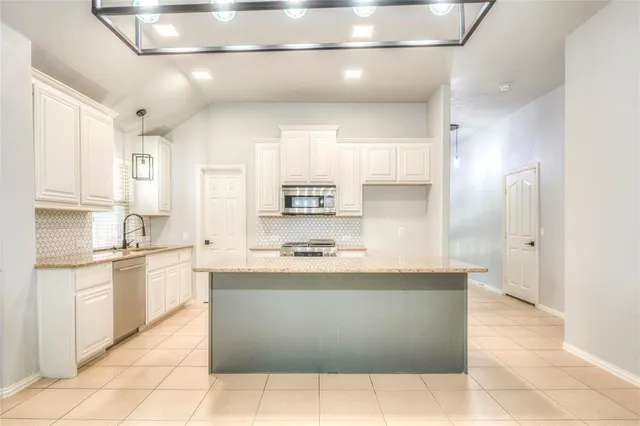 a large kitchen with stainless steel appliances a sink and cabinets