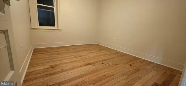a view of an empty room with wooden floor and windows