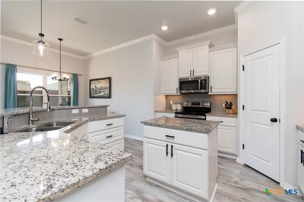 a kitchen with white cabinets and appliances