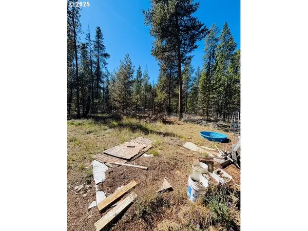 a view of a backyard with wooden fence and trees