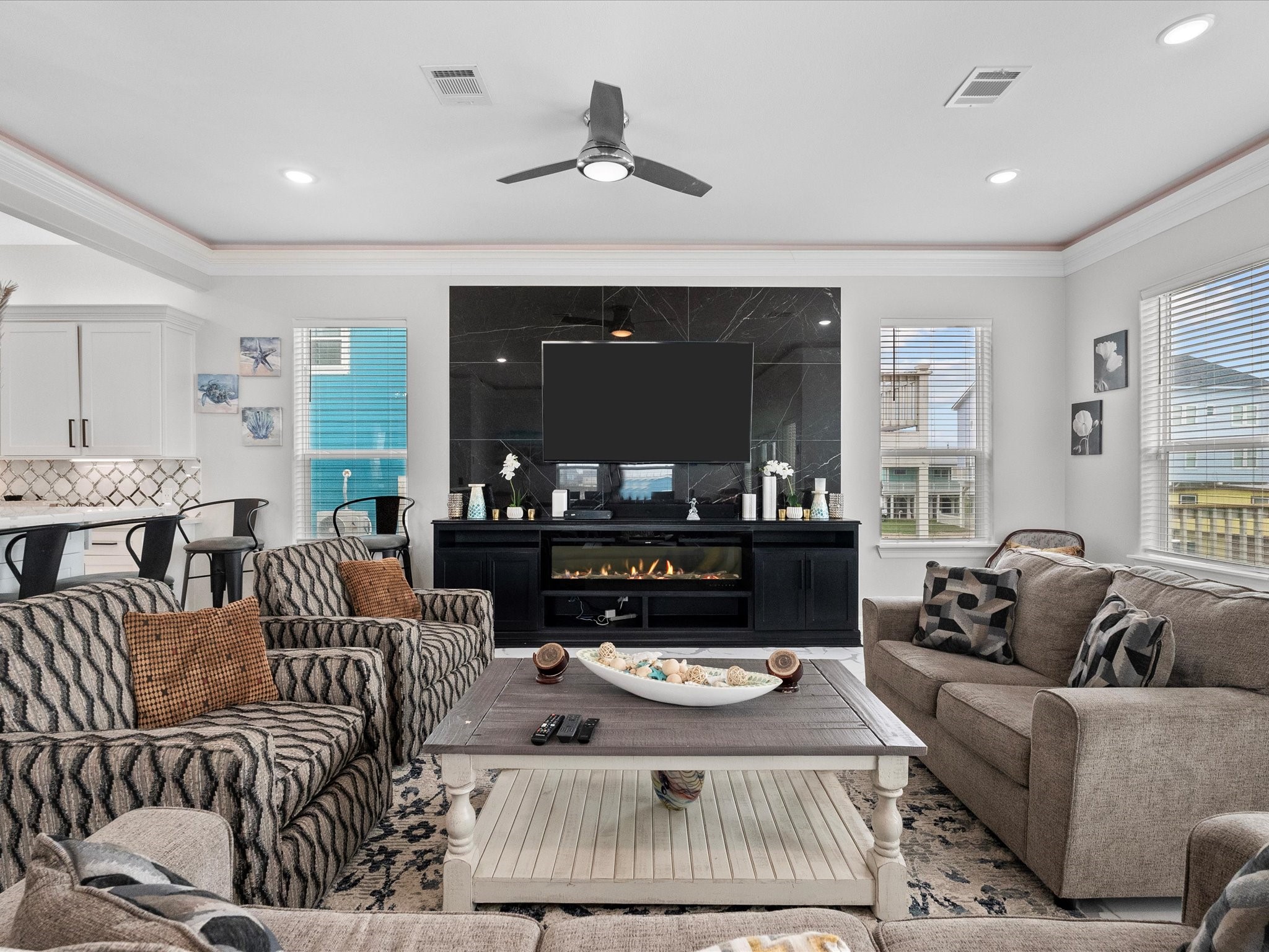 1018 Seashell Drive Surfside Beach, TX 77541 - Photo 19 of 49 This inviting living room features a modern open layout with cozy seating, a stylish fireplace, and a wall-mounted TV. Large windows allow natural light, and the adjoining kitchen creates a perfect space for entertaining.