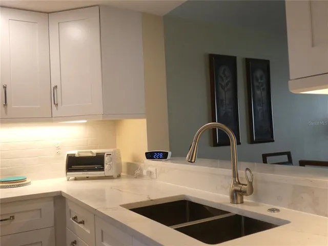 a kitchen with a sink and a stove with wooden floor
