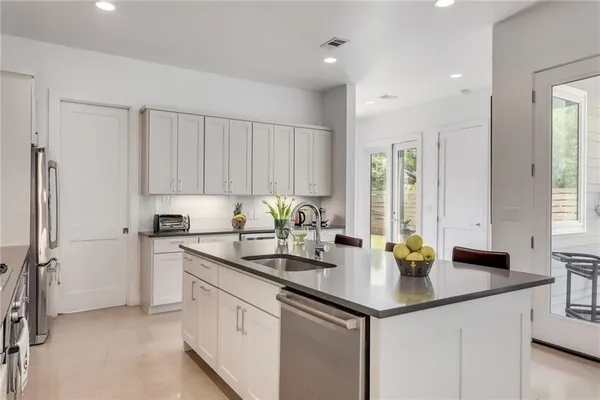a kitchen with stainless steel appliances granite countertop a sink a stove and cabinets