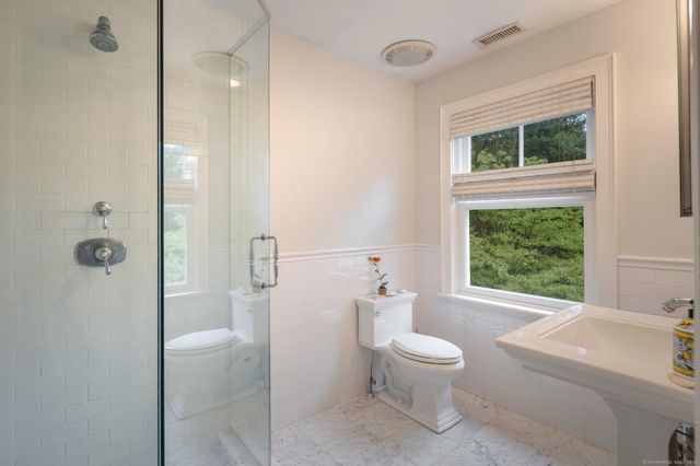 a bathroom with a toilet sink a shower and a large mirror