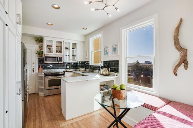 a kitchen with stainless steel appliances kitchen island granite countertop a refrigerator a stove and white cabinets with wooden floor