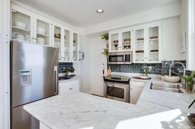 a kitchen with stainless steel appliances granite countertop a refrigerator a stove and a sink