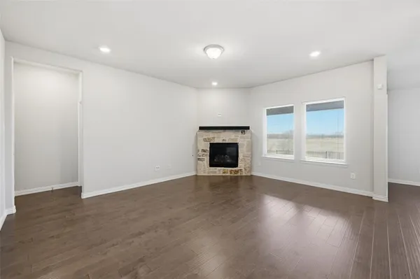 an empty room with windows and fireplace