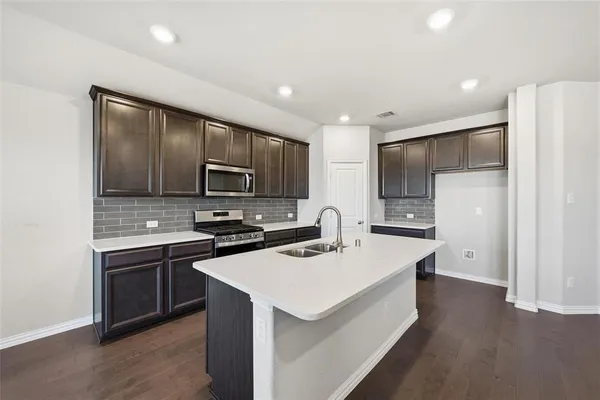 a kitchen with granite countertop a sink cabinets and stainless steel appliances