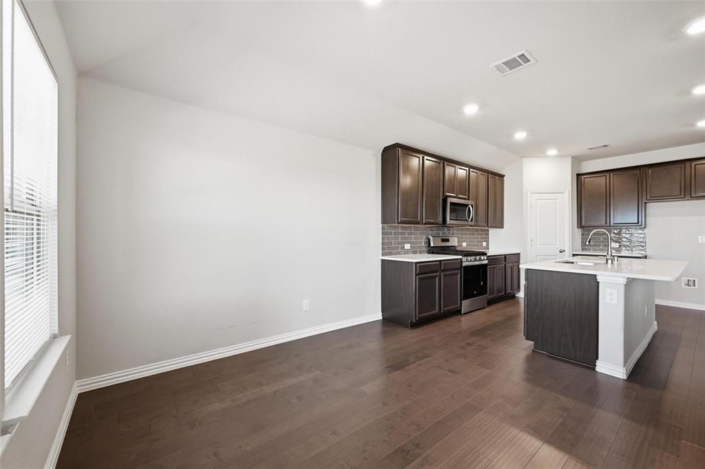 1116 Rountree Court Celina, TX 75009 - Photo 18 of 29 a kitchen with granite countertop a sink cabinets and stainless steel appliances