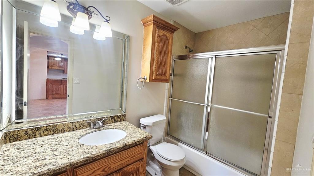 1004 West F Street Mission, TX 78572 - Photo 6 of 12 a bathroom with a granite countertop sink toilet and shower