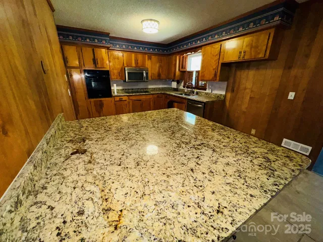 a large kitchen with a stove a refrigerator and a wooden floor