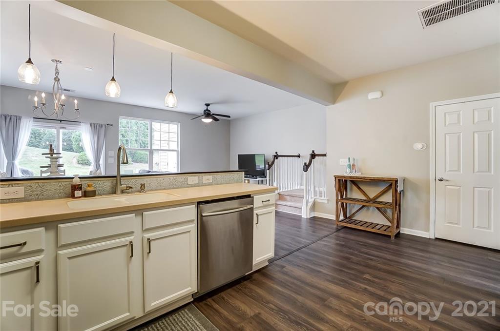 142 Council House Road Fort Mill, SC 29708 - Photo 9 of 32 a large kitchen with white cabinets a sink dishwasher a dining table and chairs with wooden floor
