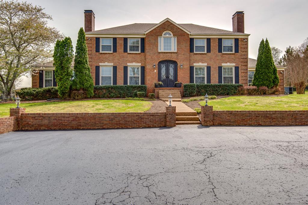a front view of a house with a yard and trees