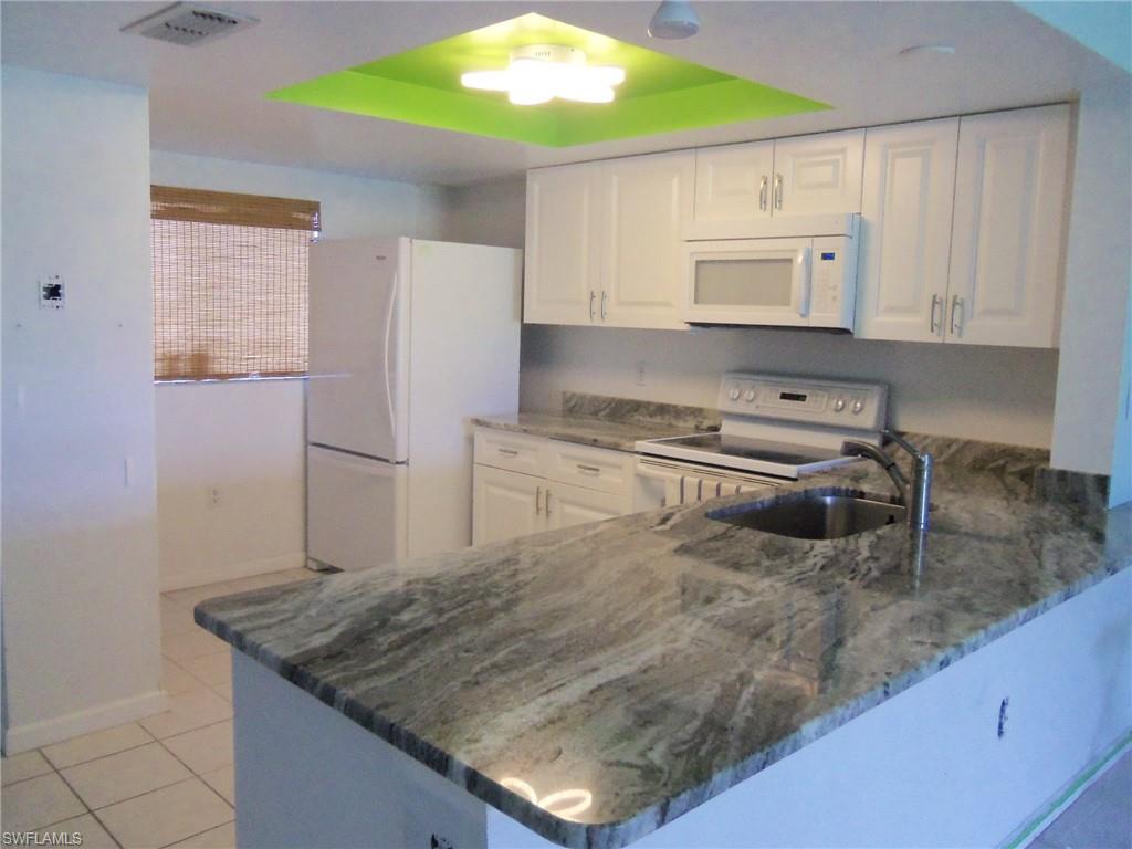 144 Cypress Way East, Unit 702 Naples, FL 34110 - Photo 1 of 18 a kitchen with a sink a stove and a refrigerator