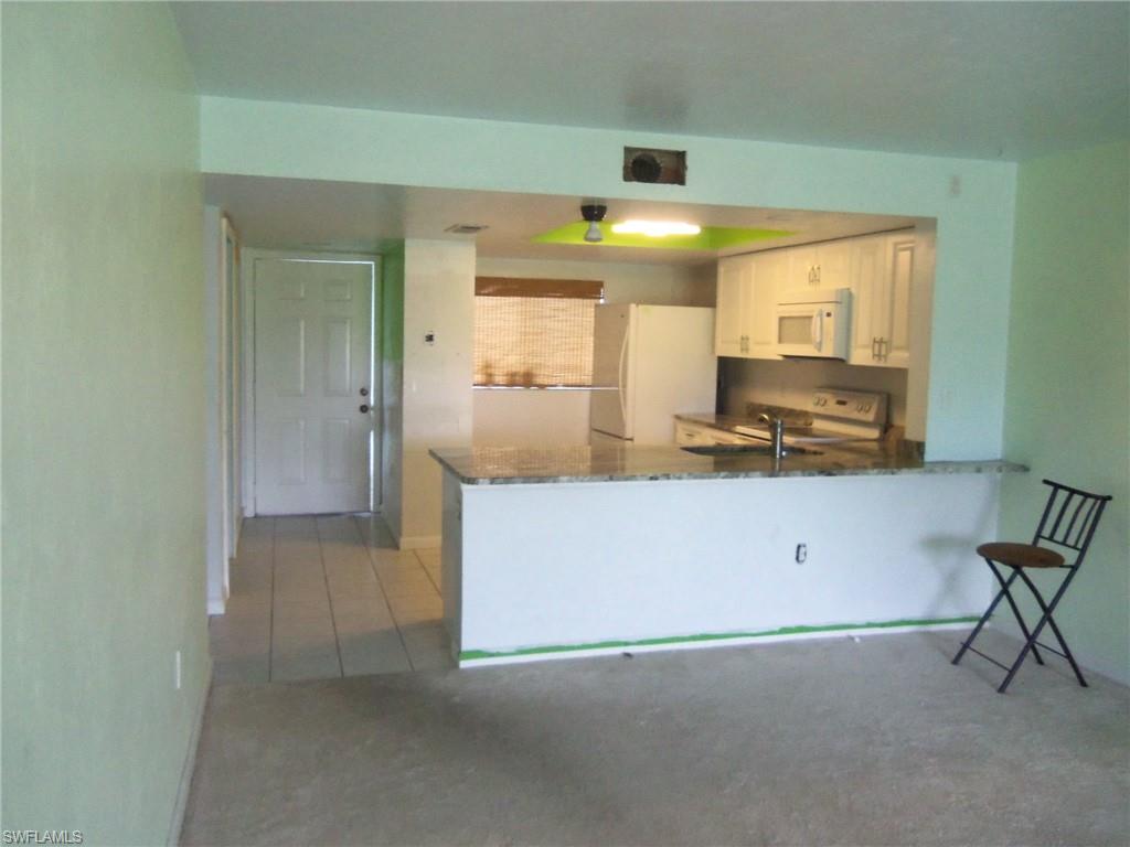 144 Cypress Way East, Unit 702 Naples, FL 34110 - Photo 2 of 18 a view of kitchen with microwave and cabinets