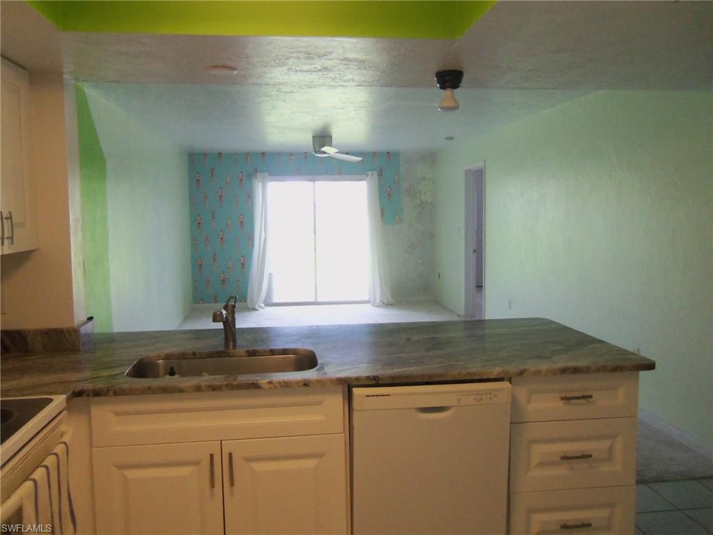 144 Cypress Way East, Unit 702 Naples, FL 34110 - Photo 3 of 18 a kitchen with granite countertop white cabinets and a sink