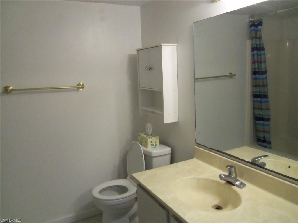 144 Cypress Way East, Unit 702 Naples, FL 34110 - Photo 8 of 18 a bathroom with a sink toilet and vanity
