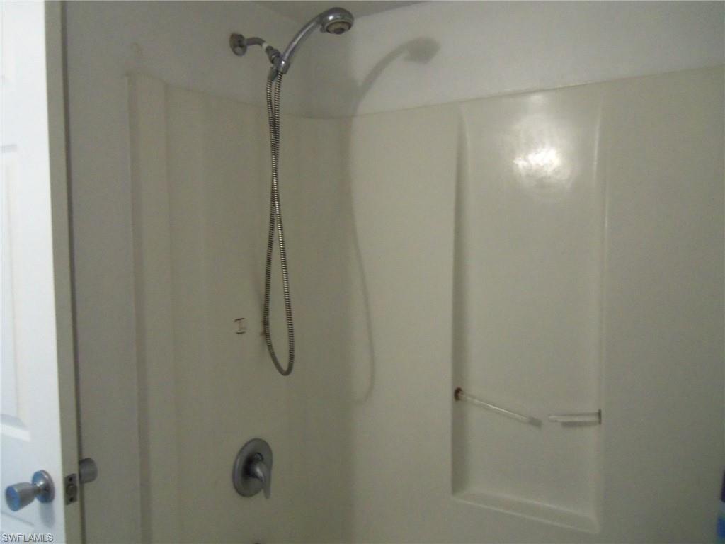 144 Cypress Way East, Unit 702 Naples, FL 34110 - Photo 9 of 18 a bathroom with a glass shower door
