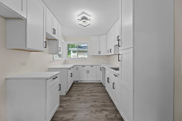 a kitchen with white cabinets appliances a sink and a window
