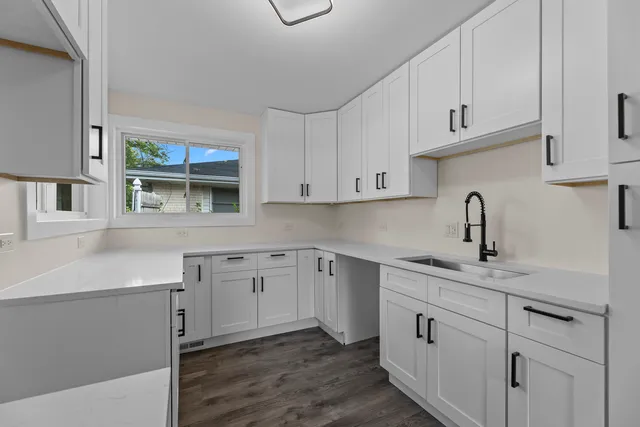 a kitchen with stainless steel appliances granite countertop white cabinets sink and window