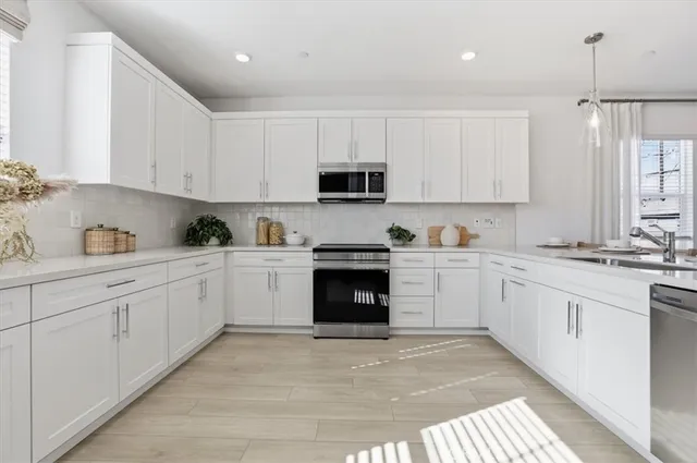 a white kitchen with granite countertop white cabinets and stainless steel appliances