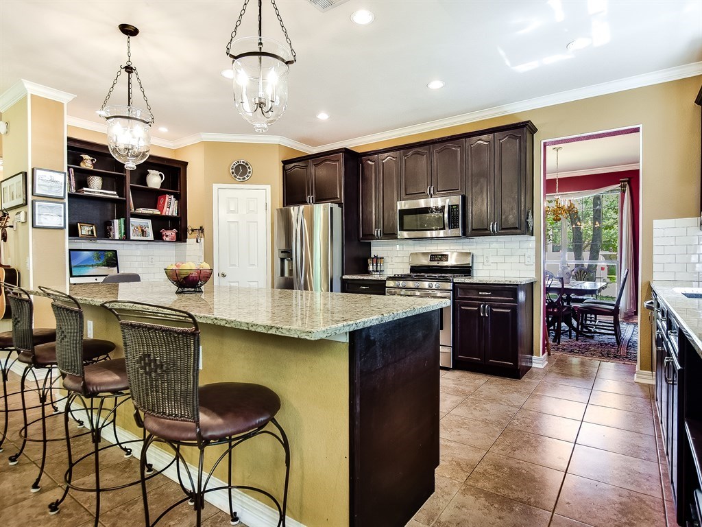 a kitchen with stainless steel appliances granite countertop a stove top oven a refrigerator a sink and a center island