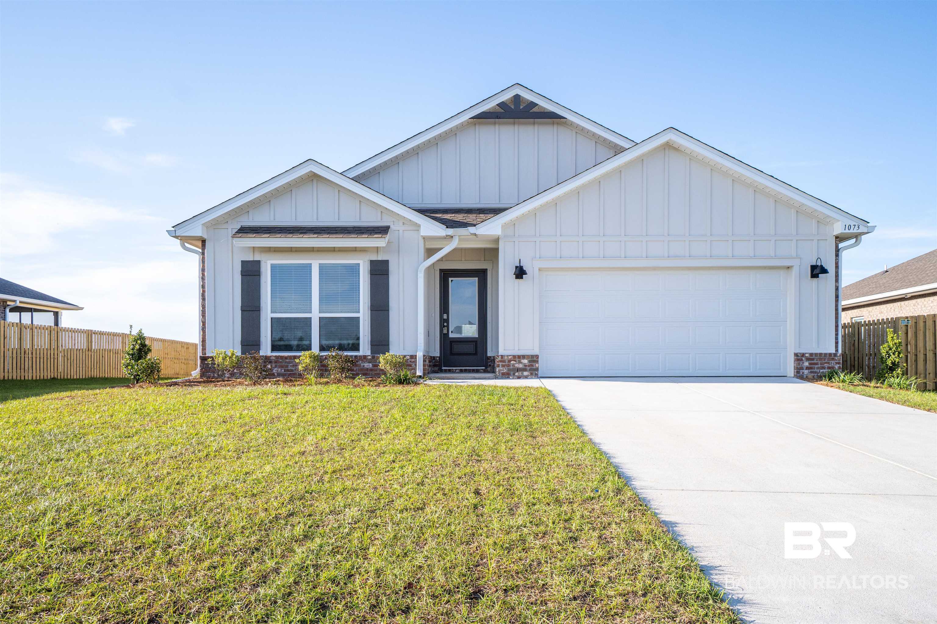 1073 Hayward Loop Foley, AL 36535 - Photo 1 of 18 Contemporary farmhouse-style exterior featuring vertical white siding, dark shutters, an attached two-car garage, a concrete driveway, and a partially bricked facade