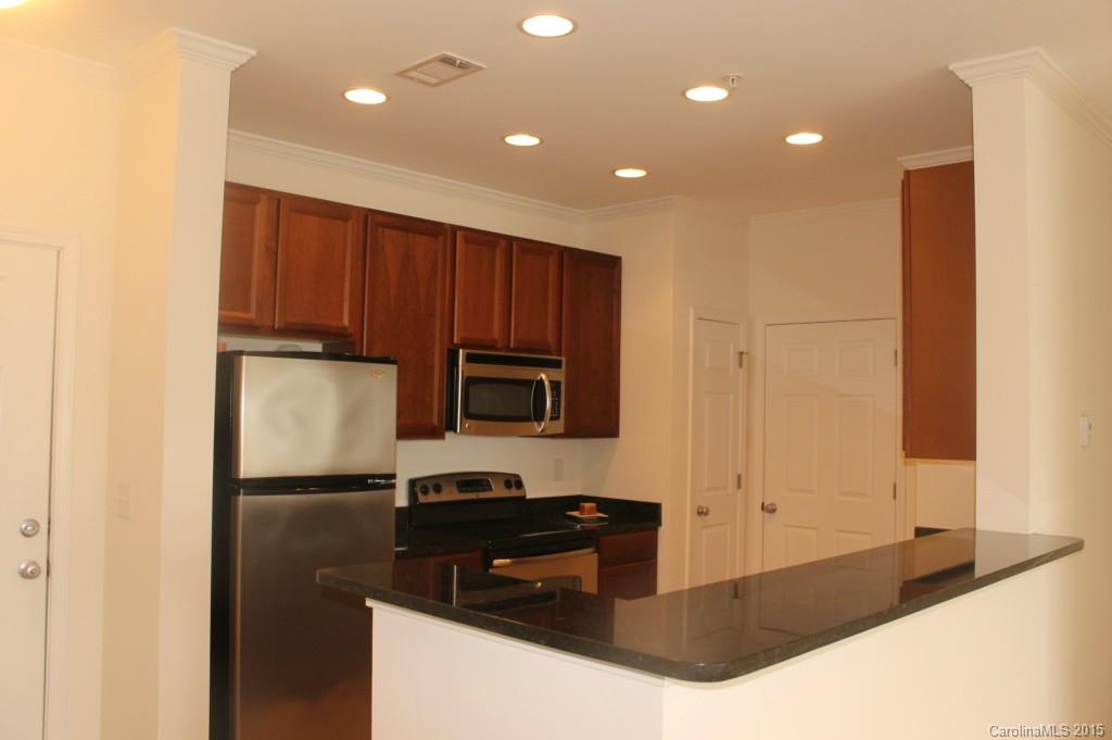 1000 East Woodlawn Road, Unit 405 Charlotte, NC 28209 - Photo 4 of 15 a kitchen with granite countertop stainless steel appliances and wooden cabinets