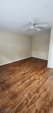 an empty room with wooden floor and fan