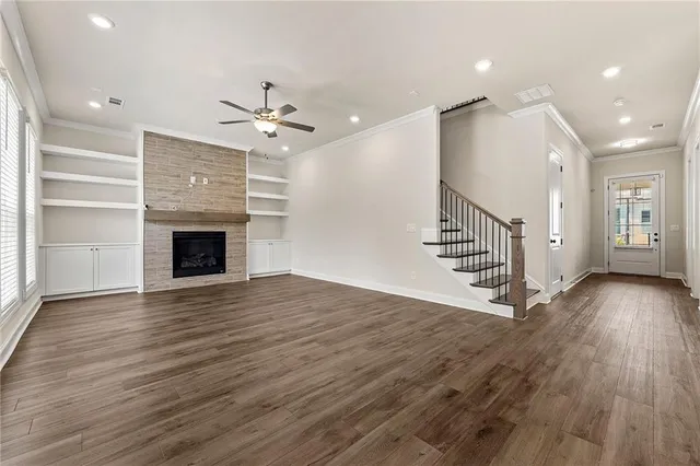 a view of an empty room with wooden floor fireplace and a window