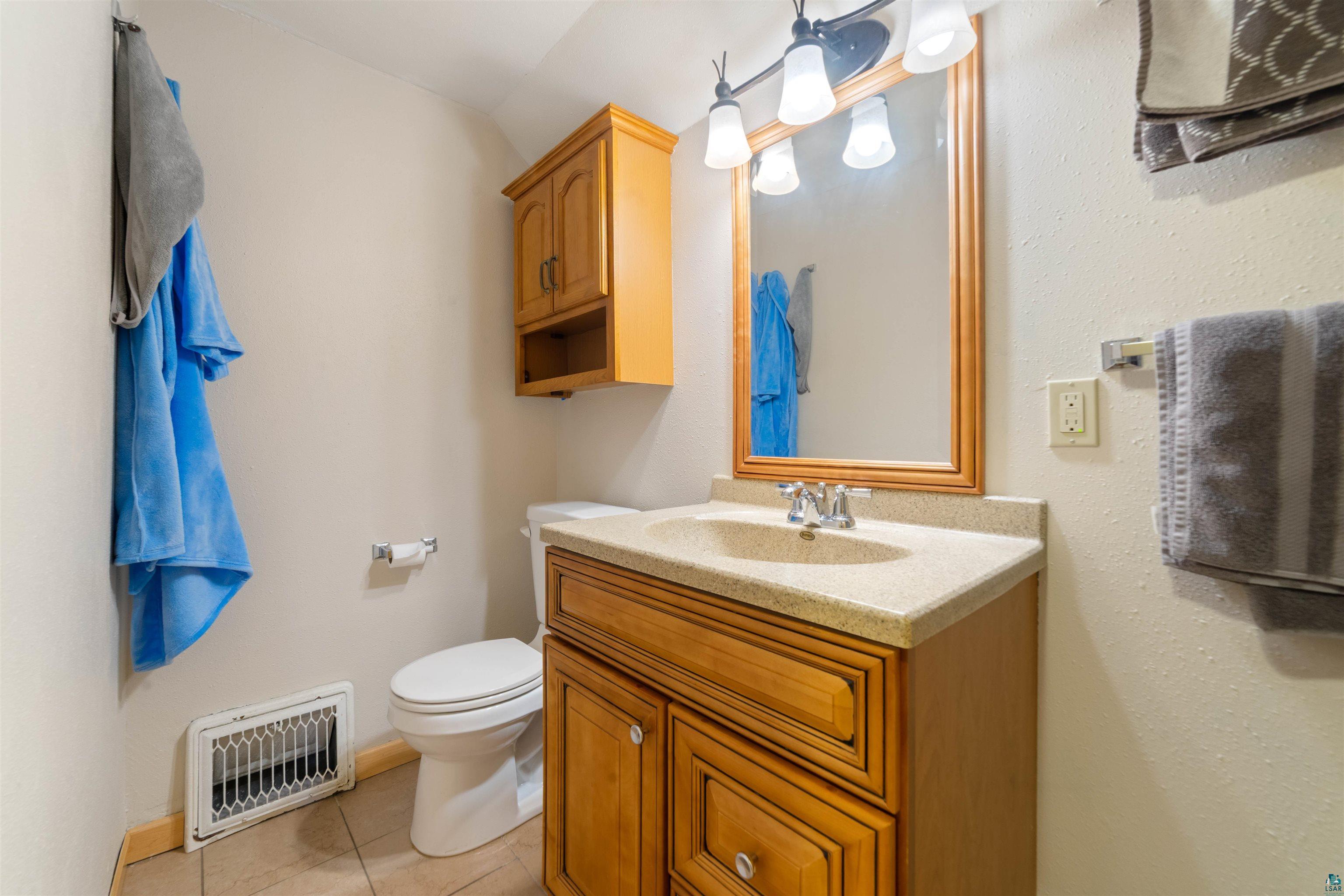 4073 Reinke Road Duluth, MN 55811 - Photo 6 of 32 Bathroom vanity featuring wood-finish cabinetry, a light-toned countertop, and a basin sink with a chrome faucet