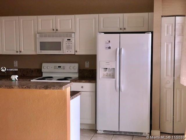 12813 Southwest 132nd Terrace Miami, FL 33186 - Photo 3 of 8 a kitchen with stainless steel appliances white cabinets and a refrigerator