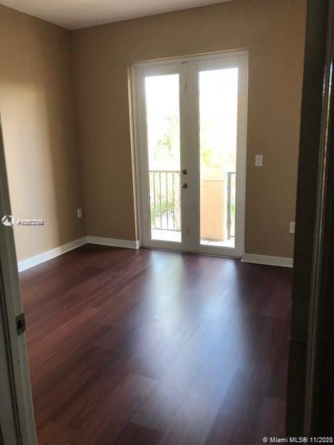 12813 Southwest 132nd Terrace Miami, FL 33186 - Photo 4 of 8 an empty room with wooden floor and windows with curtains