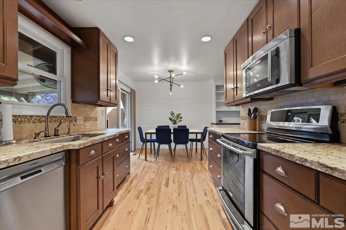 1420 Elizabeth Street Reno, NV 89509 - Photo 10 of 23 a kitchen with stainless steel appliances granite countertop a stove top oven a sink a dining table and chairs with wooden floor