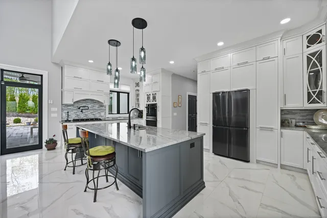 a kitchen with stainless steel appliances kitchen island granite countertop a table chairs and a refrigerator