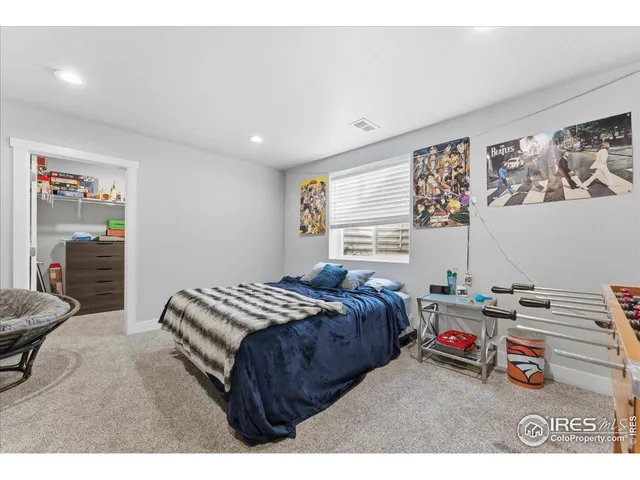 a bedroom with a bed a dresser and a painting