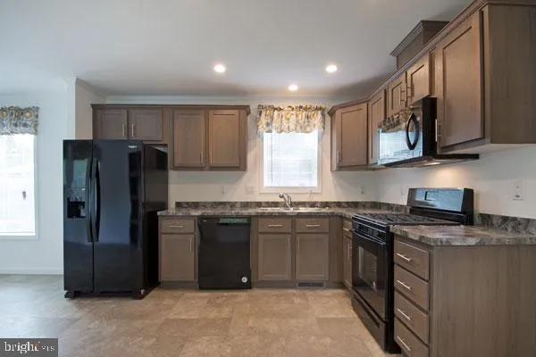 a kitchen with stainless steel appliances granite countertop a stove top oven a refrigerator and a sink