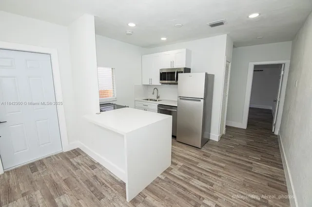 a kitchen with a refrigerator a stove top oven and wooden floor