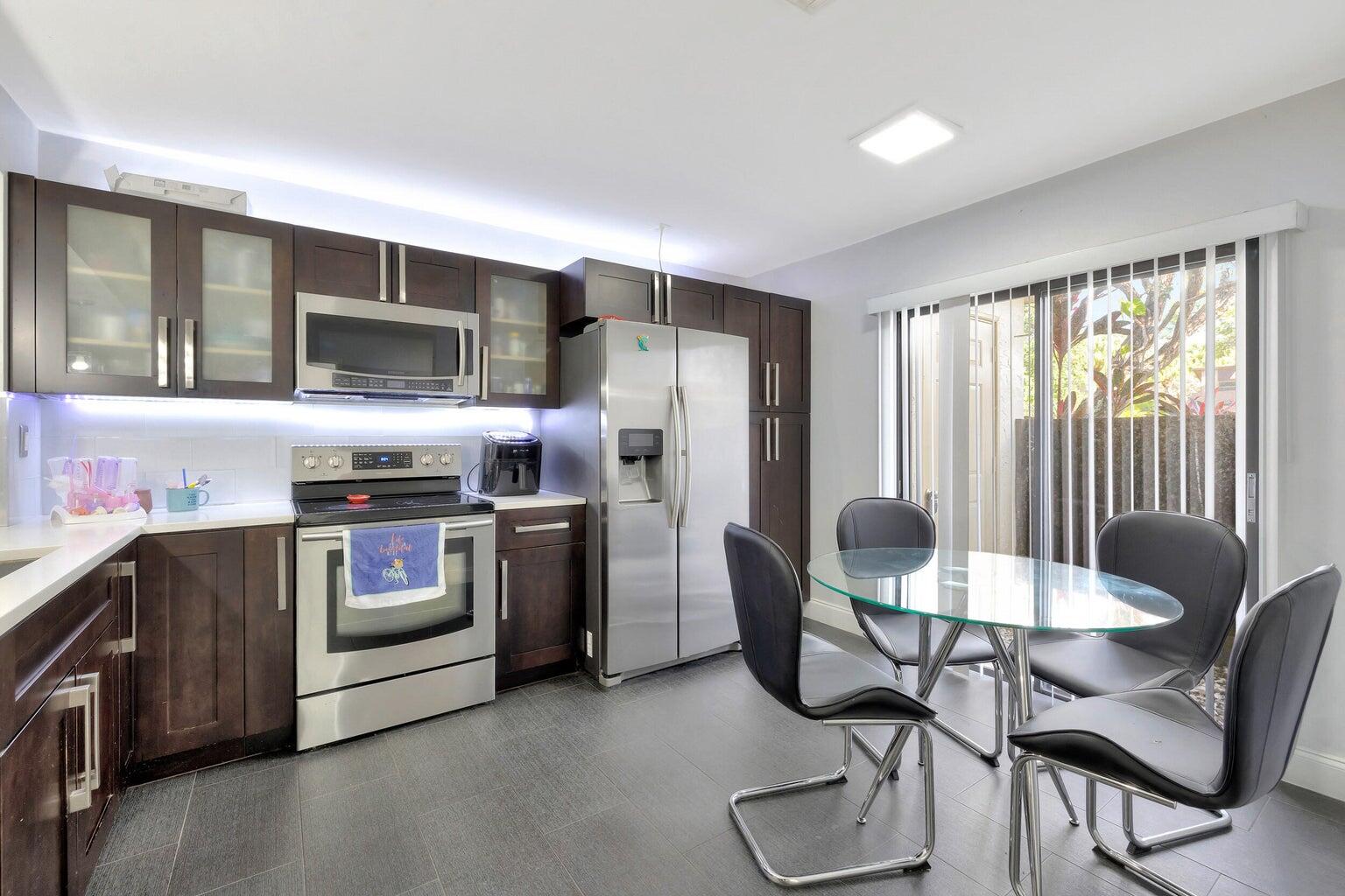 7610 Northwest 79th Avenue, Unit I5 Fort Lauderdale, FL 33321 - Photo 5 of 22 a kitchen with stainless steel appliances kitchen island granite countertop a table chairs microwave and refrigerator