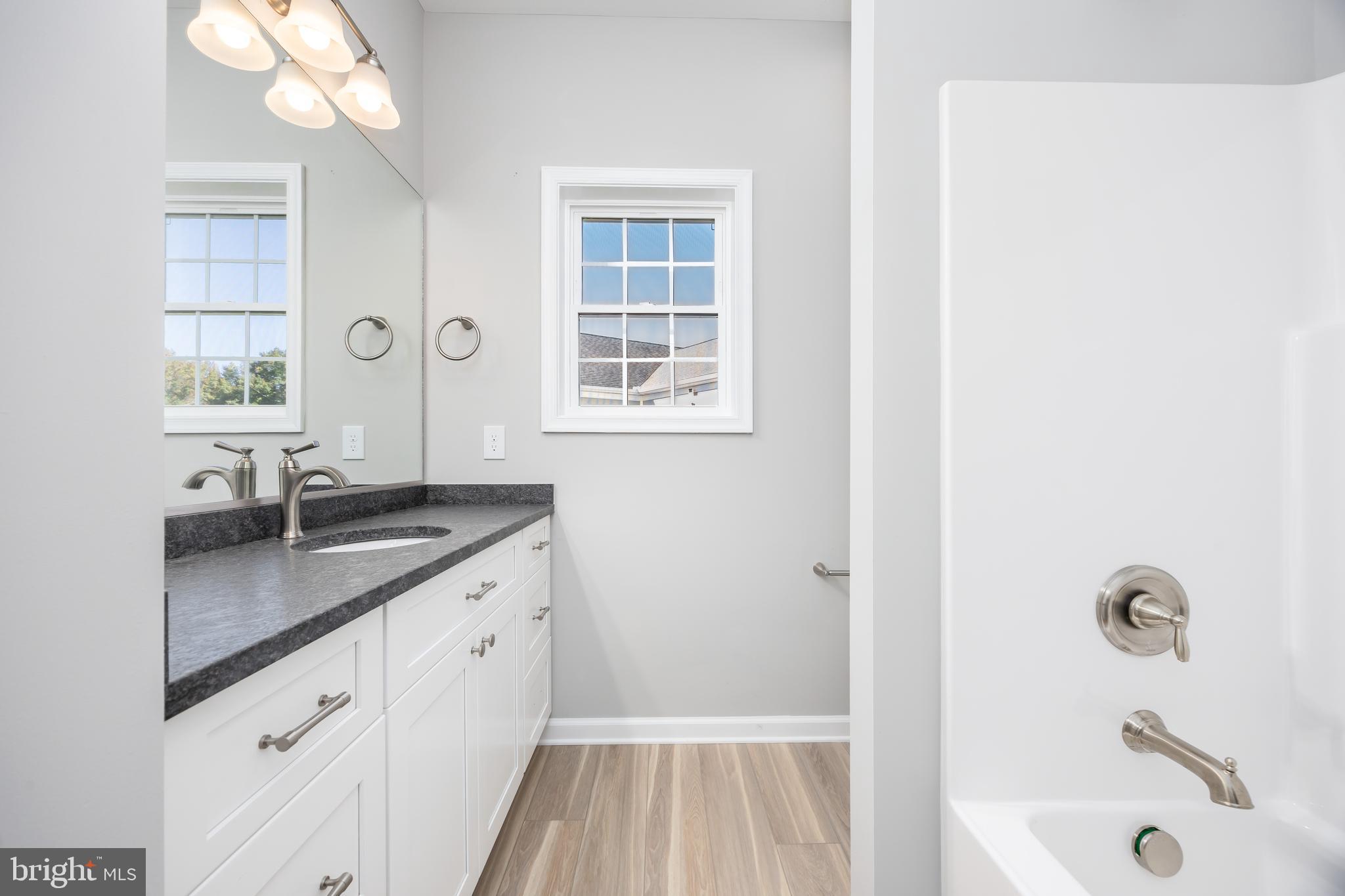 11779 St Stephens Way Princess Anne, MD 21853 - Photo 35 of 51 a bathroom with a granite countertop sink a large mirror and a bathtub