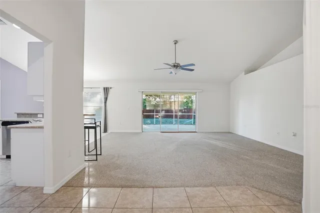 an empty room with a chandelier fan and windows