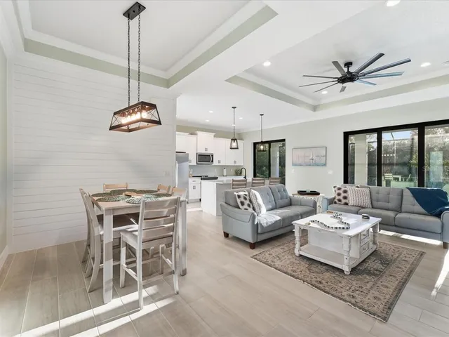 a kitchen with stainless steel appliances kitchen island granite countertop a stove a sink a dining table and chairs with wooden floor