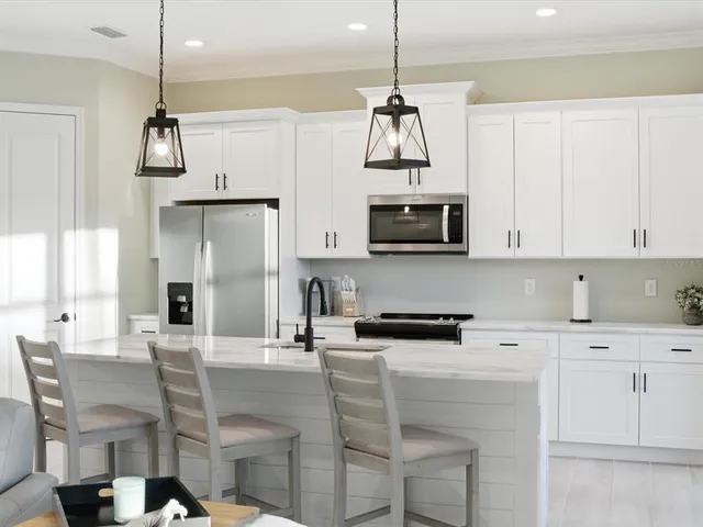 a kitchen with stainless steel appliances a stove a refrigerator a microwave oven a sink with a dining table and chairs