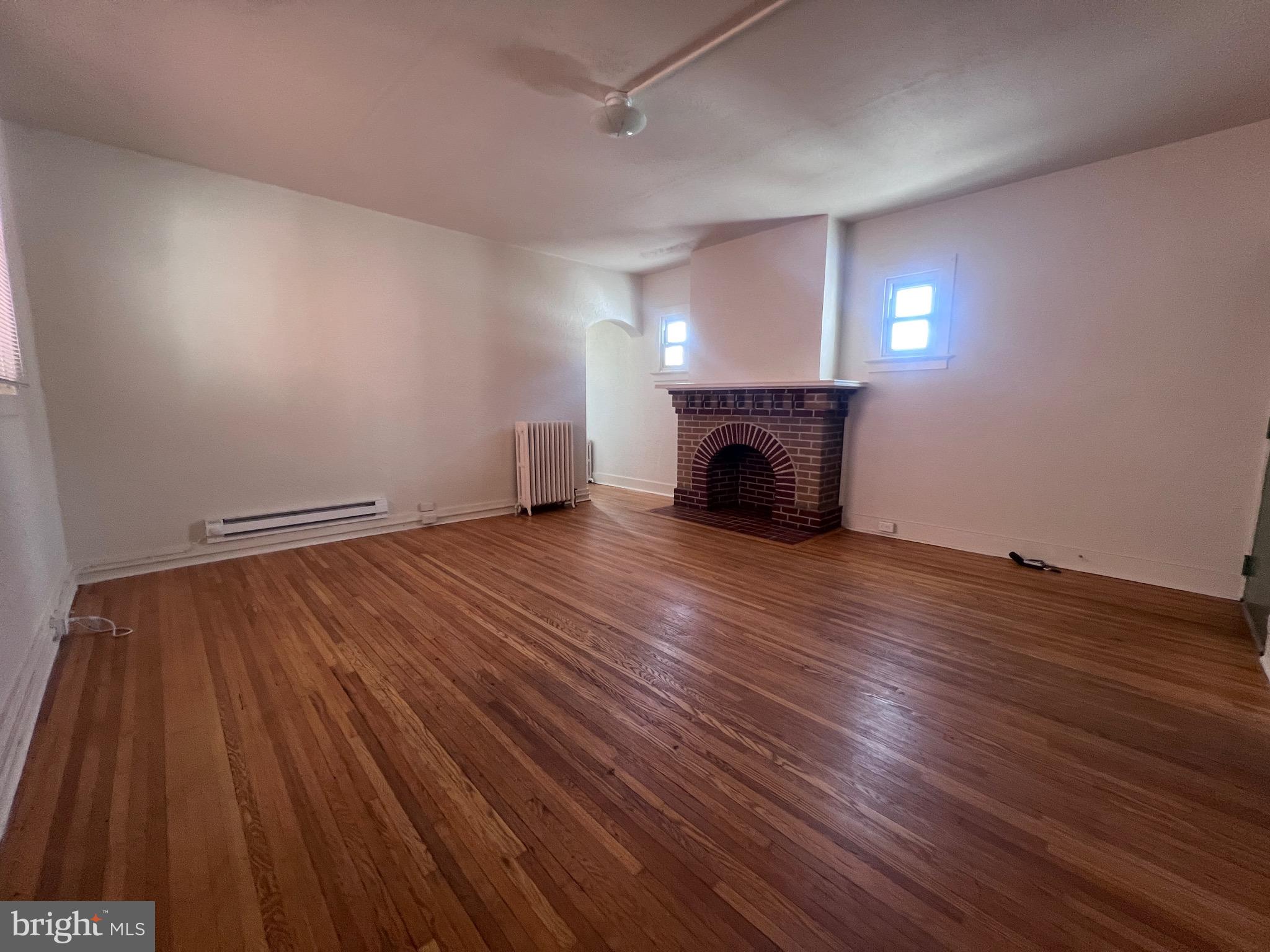 144 West Patrick Street, Unit 4 Frederick, MD 21701 - Photo 7 of 16 an empty room with wooden floor fireplace and windows