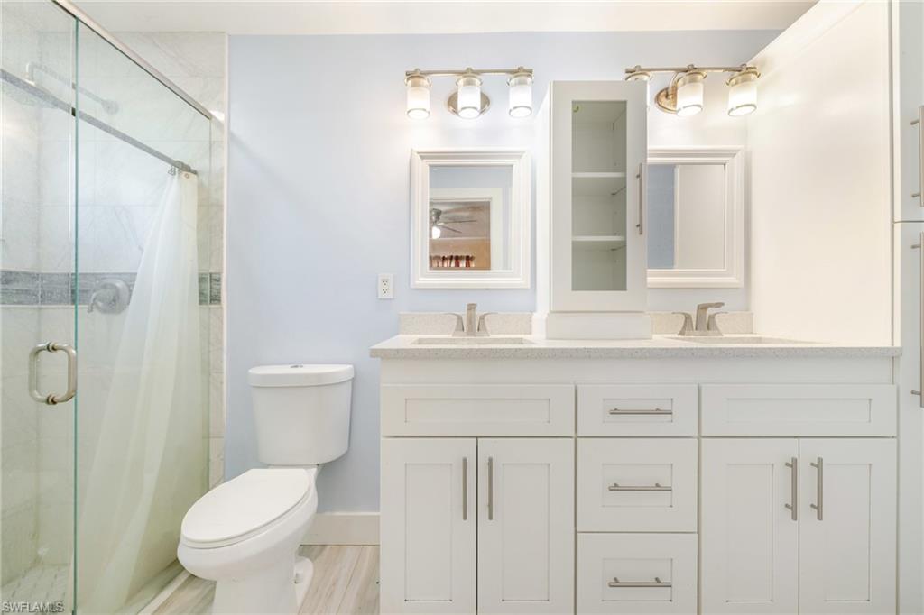 339 Beachwood Road Lehigh Acres, FL 33936 - Photo 11 of 32 Bathroom featuring a marble finish shower, double vanity, and light wood-type flooring