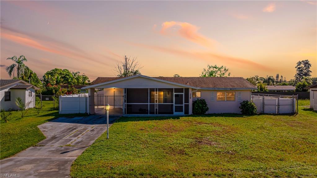 339 Beachwood Road Lehigh Acres, FL 33936 - Photo 15 of 32 View of front of home with a sunroom, stucco siding, driveway, and a gate